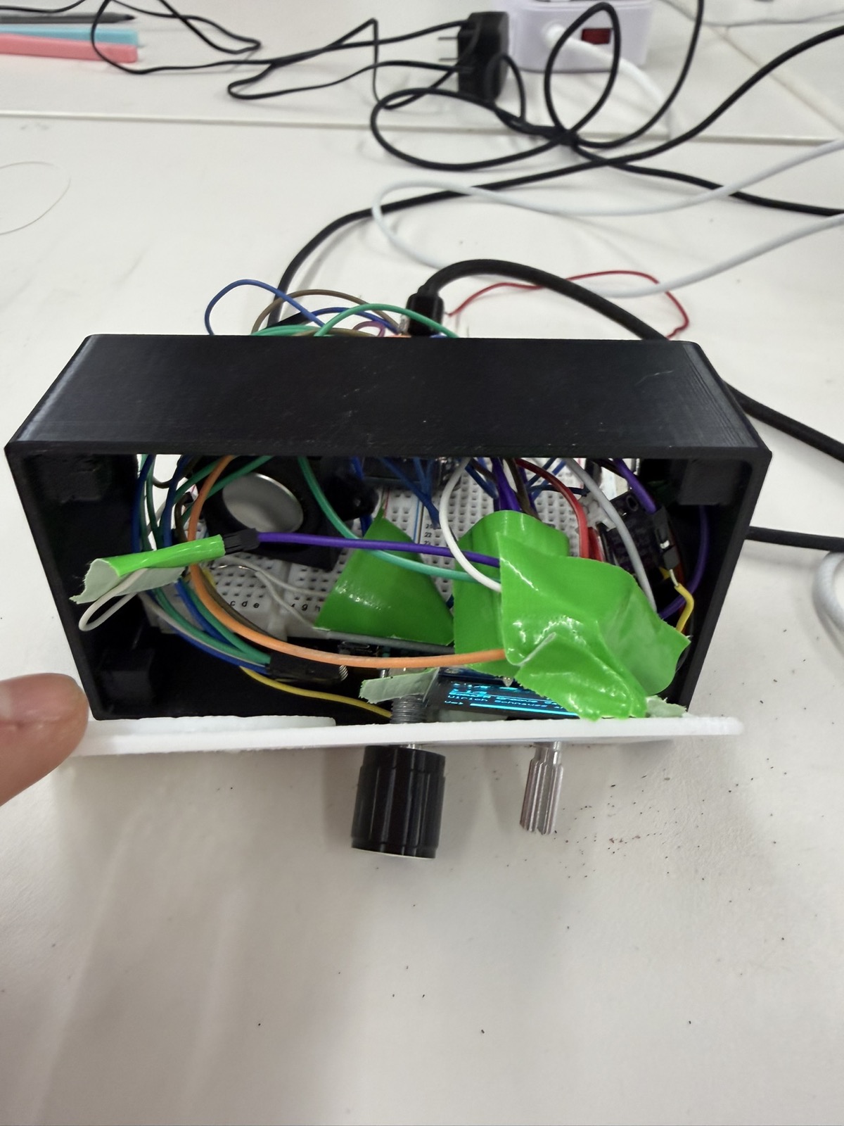 Messy taped-up radio internals with the OLED display, rotary encoder, potentiometer, and breadboard inside the enclosure