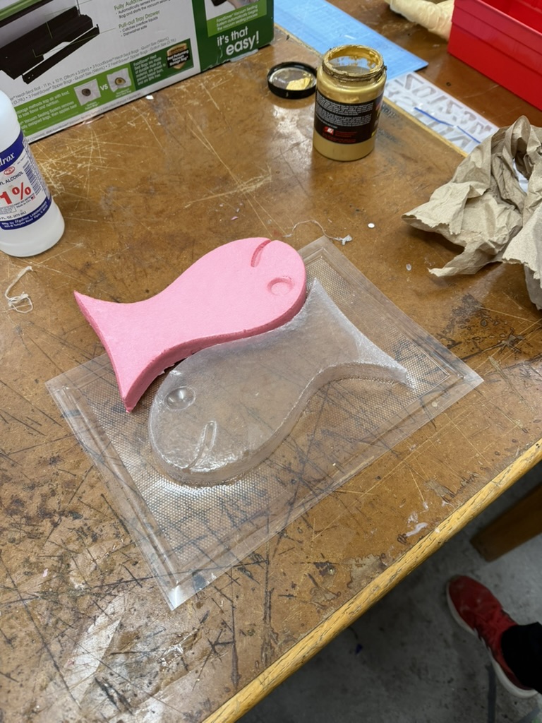 Pink foam goldfish next to the clear vacuum-formed mold
